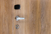 Door handle, lock, and card key reader on a wooden door.