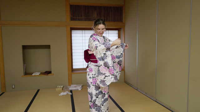 Young female tourist in kimono learning Japanese dance in Japanese tatami room - slow motion