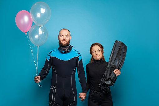 Man and woman scuba diver with pink ballon on blue background