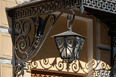 Street lamp in Art Nouveau style, attached to a wrought metal bracket against the background of a historic building.