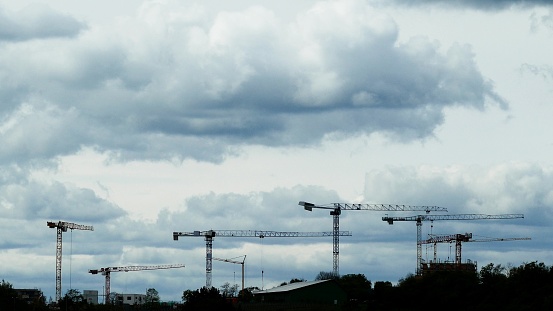 Silhouettes of moving cranes under cloudy sky