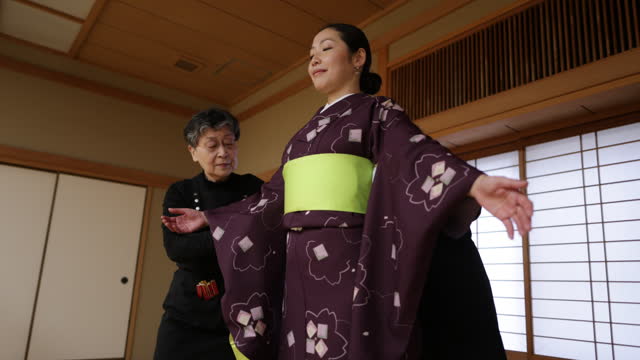 Female tourists getting kimono dressed in Japanese tatami room