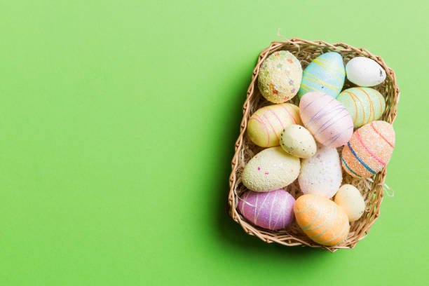 istock Colorful Easter eggs in wicker basket against colored background, closeup. top view with copy space 2149257046