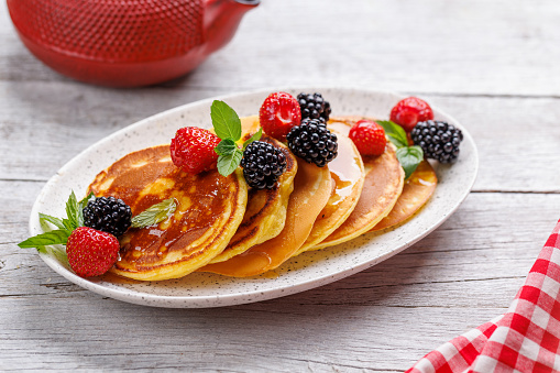 Tasty homemade pancakes with berries and honey syrup