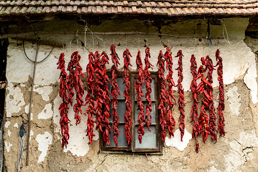 Dried red peppers hanging on a wall of an old house.