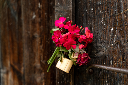 Red flowers on the doorknob on a wooden door outdoors.
