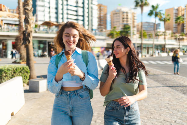 istock Two female friends having fun while eating ice cream by the sea 2149261408