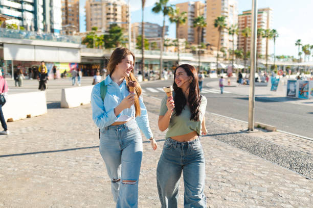 istock Two female friends having fun while eating ice cream by the sea 2149261415
