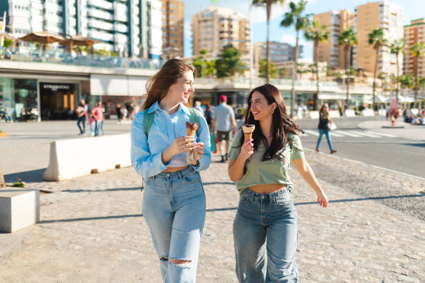 istock Two female friends having fun while eating ice cream by the sea 2149261417