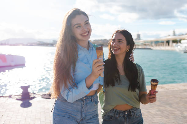 istock Two female friends having fun while eating ice cream by the sea 2149261439