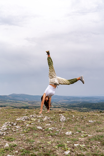 Young woman doing a handstand on the rocky mountain in Serbia.