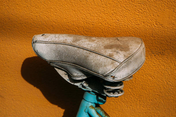 old bicycle seat in close-up against an orange wall