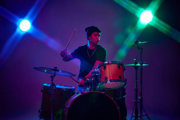 istock Contemporary drummer playing with joy in pink-purple stage lighting against gradient studio background. 2149263707