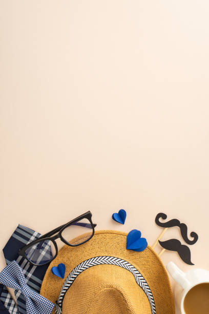 istock Commemorate Dad's special day with this festive vertical top view display: straw hat, classy tie, glasses, mustache props, hearts arranged on gentle beige surface. Great for expressing warm wishes 2149267187