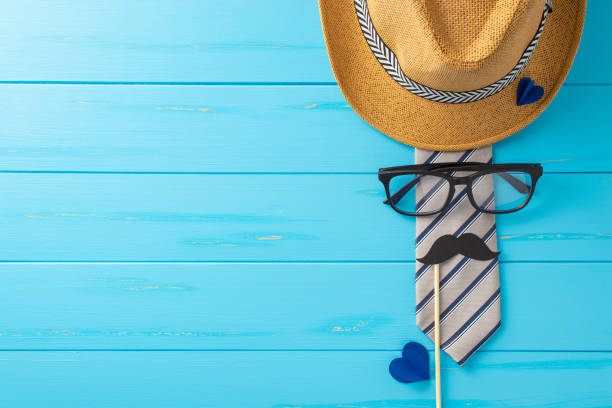 istock Get ready for a Father's Day celebration! Top-view shot featuring stylish fedora, classy tie, spectacles, faux mustaches, and heart-shaped cutouts on rustic blue backdrop, perfect for messages or ads 2149267190