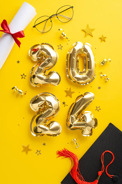 istock Educational achievement scene. Top-view vertical image featuring 2024 metallic balloons, graduation hat, diploma bound with ribbon, glasses, and shimmering confetti on dynamic yellow background 2149267237