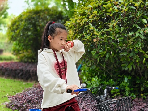 Little girl uses smart watch to answer phone while cycling in park