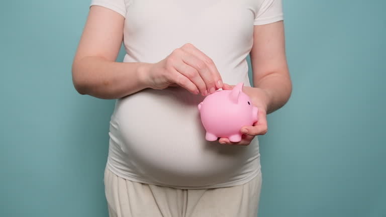 Pregnant woman holding piggy bank of money, studio blue background. The concept of pregnancy and saving money for childbirth