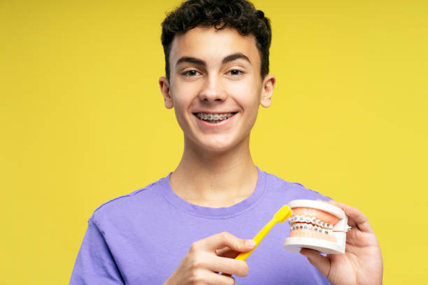 istock Smiling handsome boy with braces holding orthodontic jaw, toothbrush, brushing teeth 2149269886