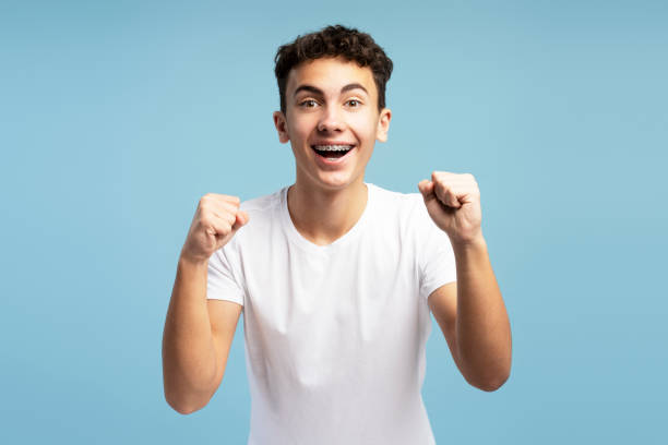 istock Happy excited fan boy with braces cheering, hands up, open mouth looking at camera 2149269937