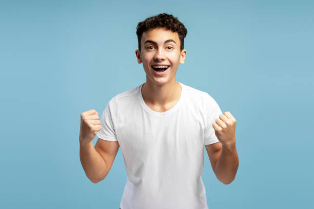 istock Smiling, excited fan boy with braces cheering, hands up, open mouth looking at camera 2149269992