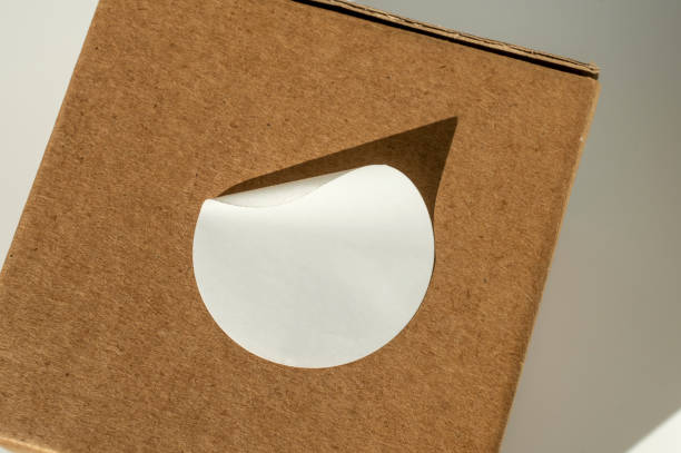 Brown cardboard box with circular white sticker on a neutral background.