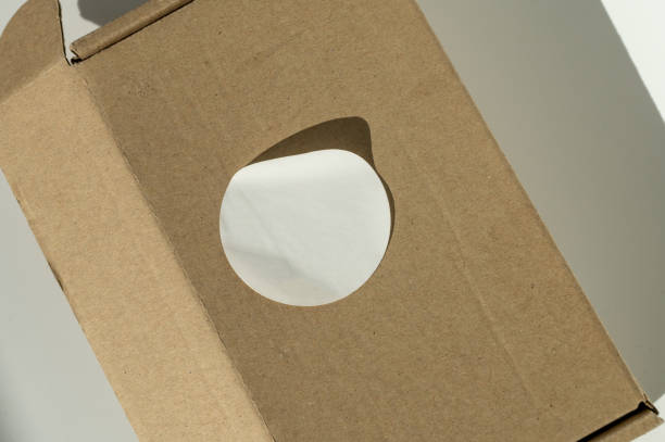istock Brown cardboard box with circular white sticker on a neutral background. 2149270368