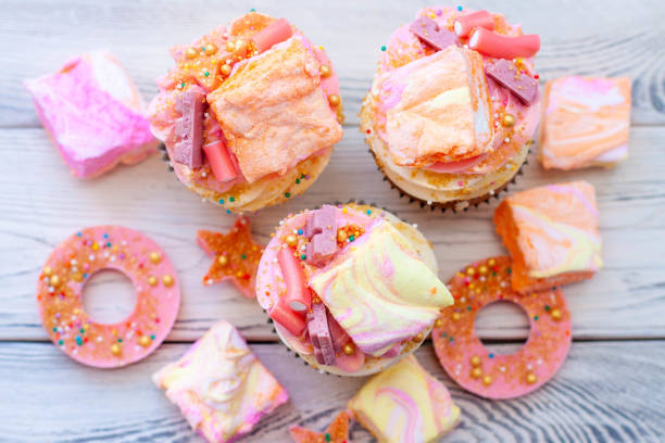 istock Pastel colored pink cupcakes with chocolate, donuts and rainbow marshmallow 2149270934