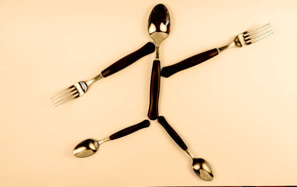 cutlery arranged to represent a little man running with a harried or desperate expression, on a white background