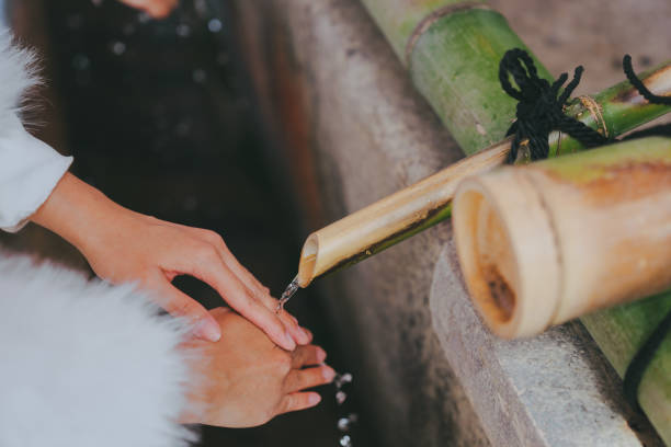 A person washing their hands with water flowing from a bamboo pipe.