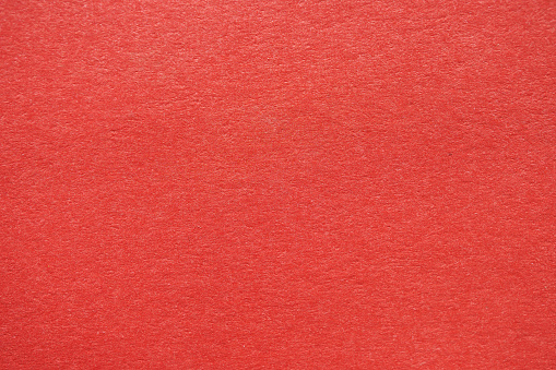 Close-up view of bright red textured paper, perfect for backgrounds or graphic design projects.