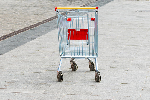 an empty shopping cart stands on the sidewalk. the concept of people lacking money for purchases. economic crisis. Shopping trolley. close-up