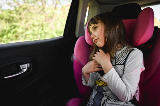 istock Cute girl sitting on a back seat into car and looking throw window. 2149276364