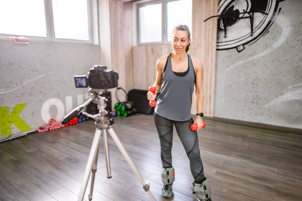 istock Fitness instructor filming a video while working out with weights at the fitness studio 2149276557