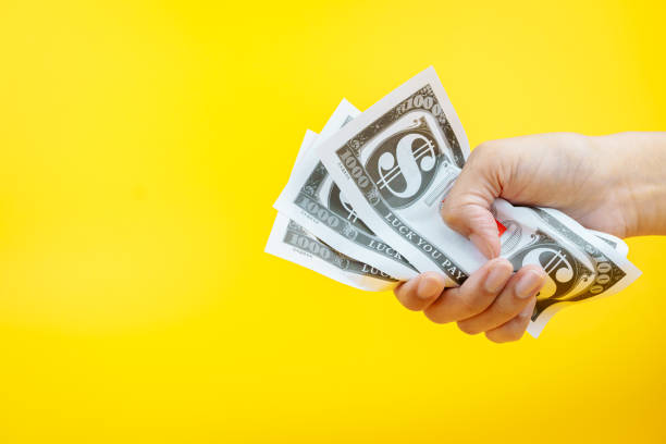 istock Female hands holding banknotes on a yellow background. 2149276735