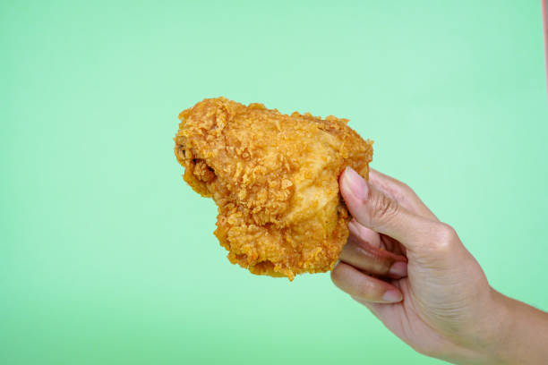 istock Female hand holding fried chicken on green background. 2149277006
