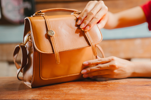 A brown leather handbag with a gold button closure.