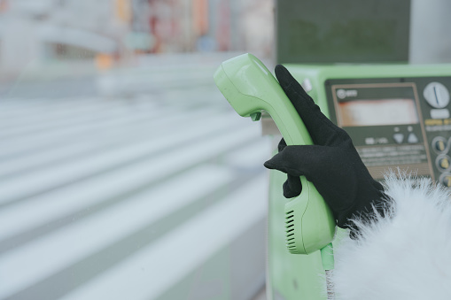 A gloved hand holding a green phone receiver