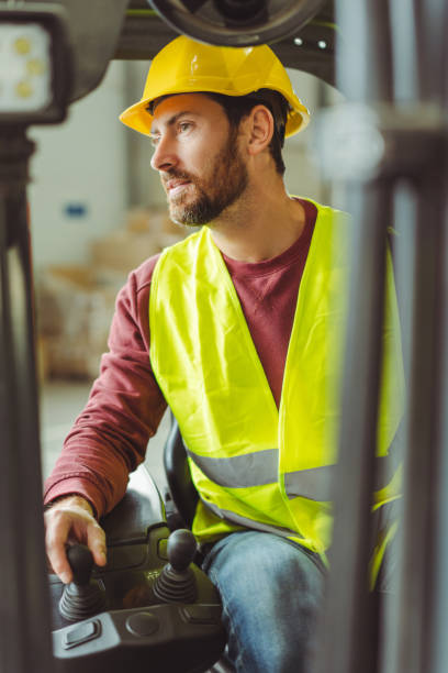 istock Attractive man, operator, driver wearing hard hat, workwear drives forklift, working in warehouse 2149277453