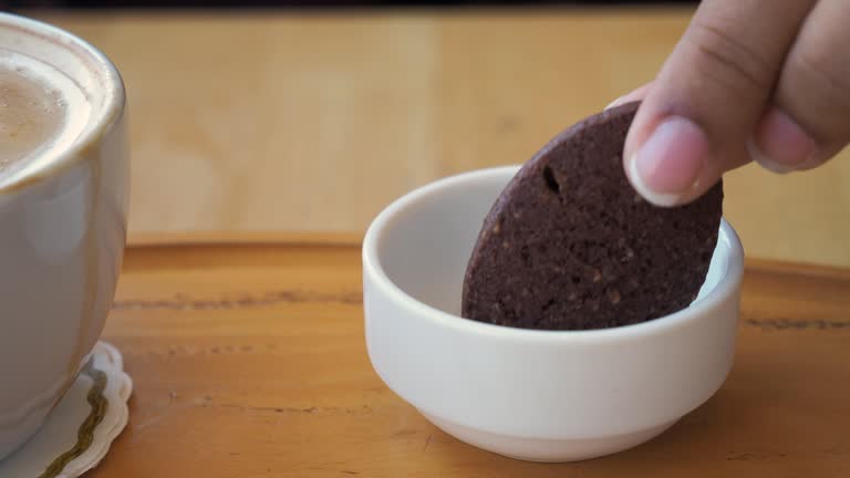hand pick a sweet chocolate cookie. a coffee cup on table