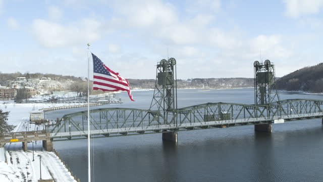 Aerial orbit around waving USA flag and historic lift bridge in Stillwater