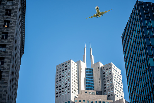 Plane passing above skyscrapers in San Francisco during springtime day, seen directly from below