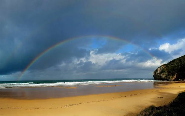 istock Stunning Seascape with Vibrant Rainbow, Sandy Beach, and Dramatic Sky Creates a Mesmerizing Scene Along the Coastline, Offering a Serene and Captivating View for Relaxation and Inspiration. 2149284877