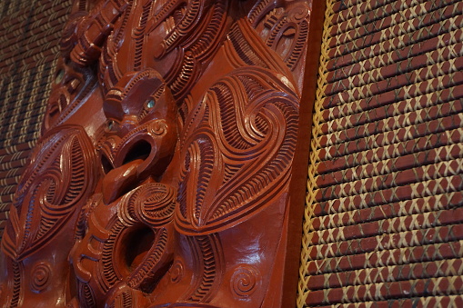 New Zealand maori carvings with woven panels on wall in a traditional meeting house