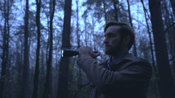 istock Detective looks for evidence in a rainy forest with a flashlight in hand, conducting an investigation 2149285637