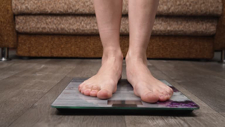 Female checking barefoot body overweight. Women on scales measure weight close up