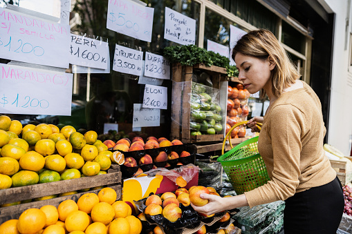 Young female customer selecting fruits and vegetables in the greengrocer's shop