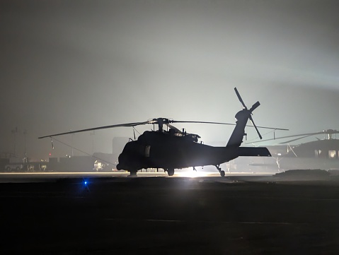 An HH-60 sits ready to take off in the fogging dusk of night
