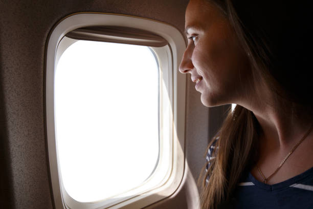 istock Young smiling woman looking through the plane window with white space 2149291773
