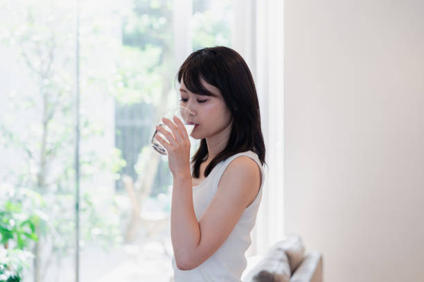 istock Young woman drinking water at home 2149292368